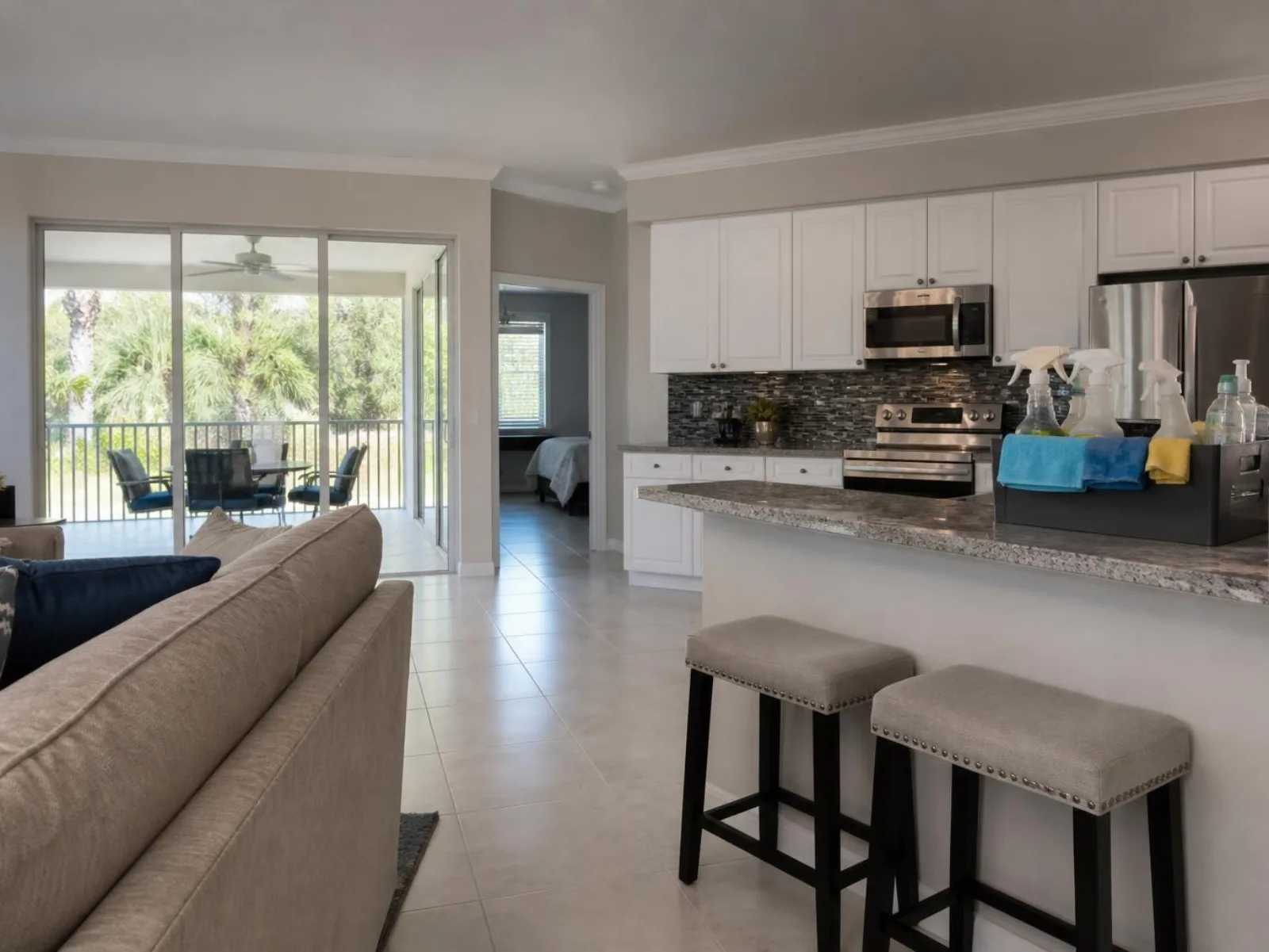 Bright open-plan Florida home interior with a cleaning caddy of supplies on the kitchen counter